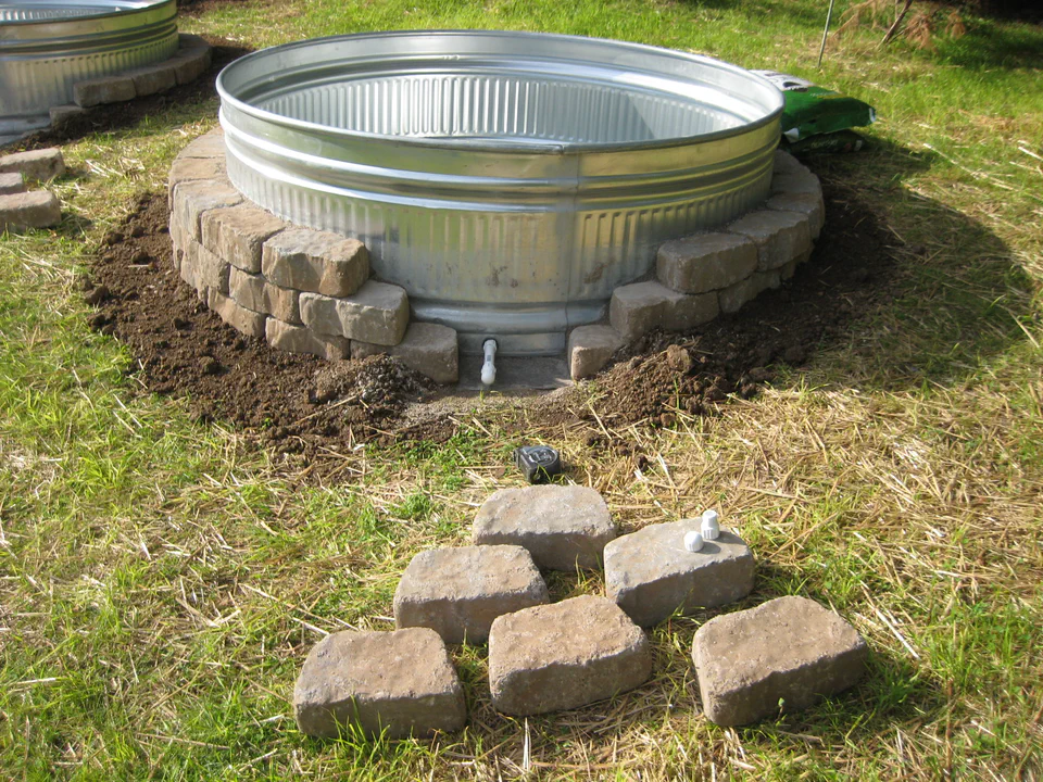 Backfilling the stone surround. The bulkhead fitting low on the tank wall provides a way to drain the gardens if ever needed.