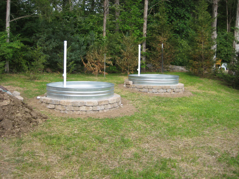 Both tanks sited at the edge of the woods, risers up. Sadly those leyland cypress trees in the background could've used a wicking watering system.