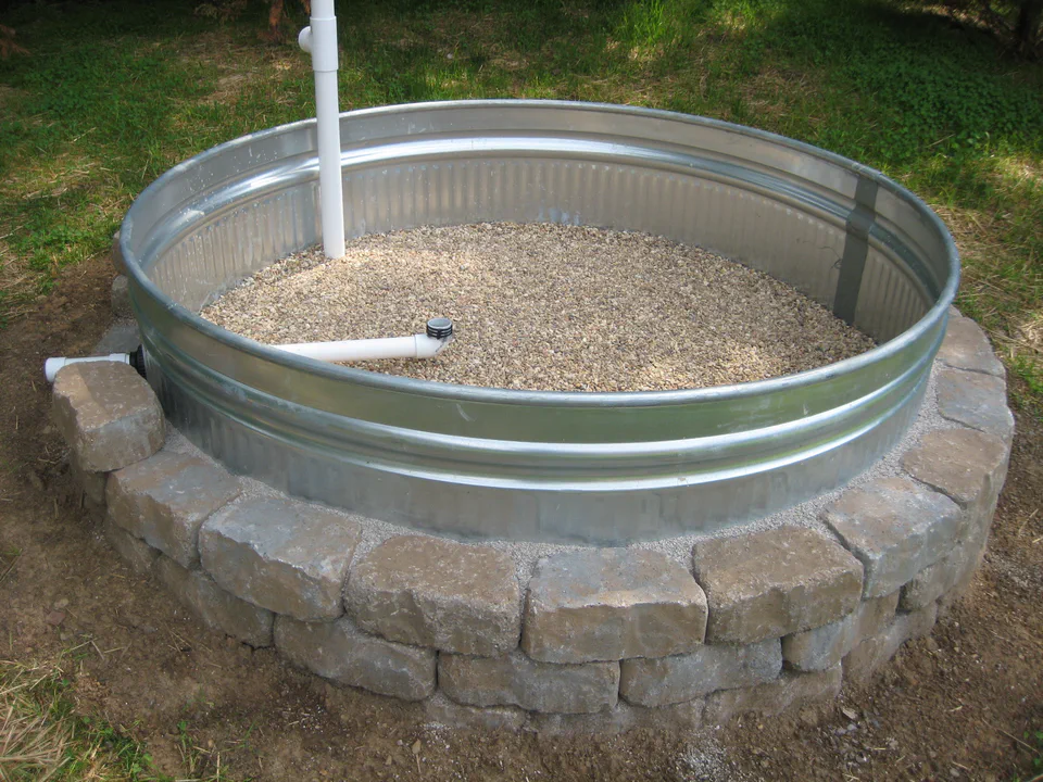 Pea gravel poured over the manifold. This is the reservoir the bed wicks from. The side overflow outlet sets the maximum water level and spills the rest, so the bed can't waterlog.