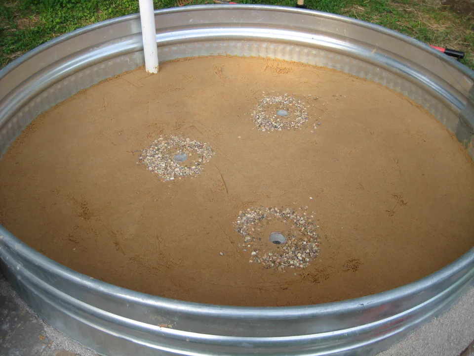 Three gravel wicking wells set into the sand — columns that pull water up toward the root zone.