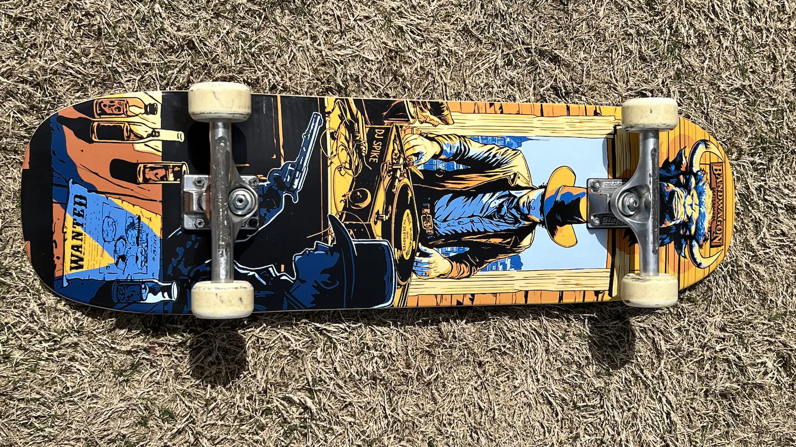A skateboard deck with a graphic of a western cowboy DJ spinning a record on a turntable; my name is printed tiny on the record.
